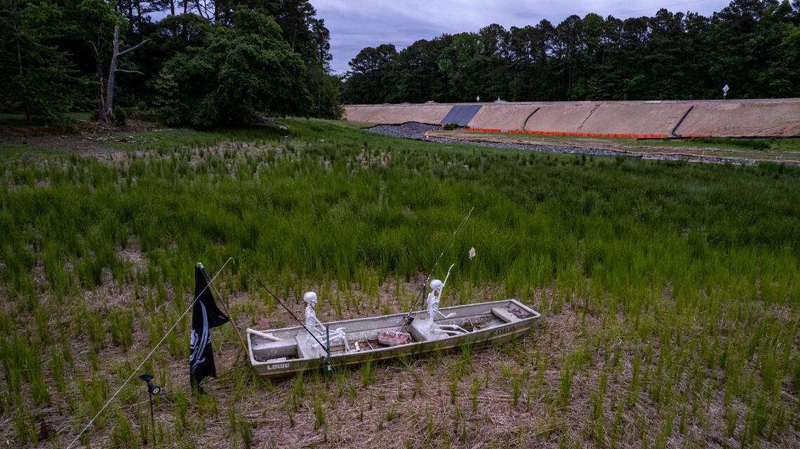 A pair of prop skeletons fish from a jon boat on the former White Oak Lake near the Beltline in West Raleigh. The N.C. Department of Transportation drained the lake last year as part of the effort to widen the Beltline between Wade Avenue and Interstate 40.
