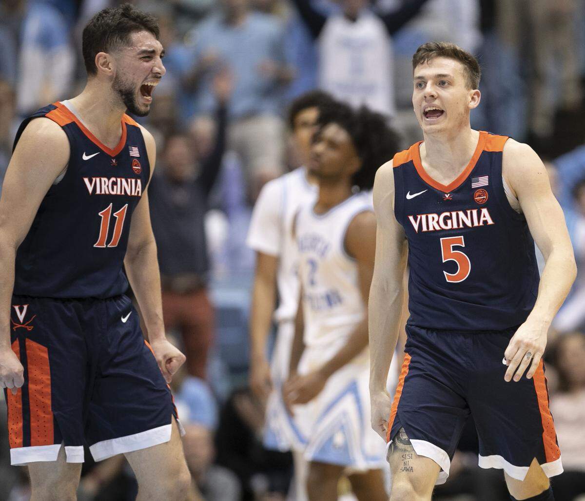 Virginia’s Kyle Guy (5) and teammate Ty Jerome (11) react after Guy hit a 3-pointer with 1:10 to seal the Cavaliers’ 69-61 victory over North Carolina on Monday, February 11, 2019 at the Smith Center in Chapel Hill, N.C.