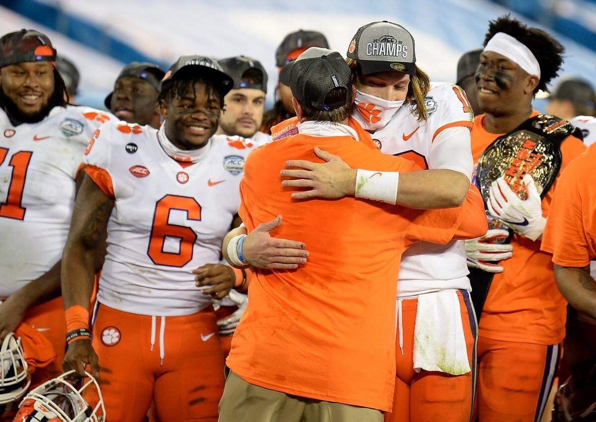Clemson Tigers head coach Dabo Swinney, back to camera, hugs quarterback Trevor Lawrence following the teamÕs victory over Notre Dame in the ACC Championship game at Bank of America Stadium in Charlotte, NC on Saturday, December 19, 2020. The Tigers defeated the Fighting Irish 34-10.
