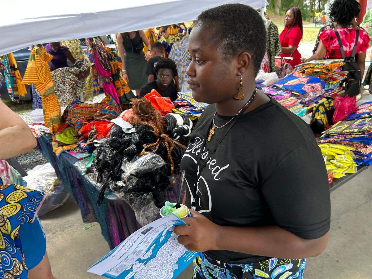 Elodie Deneassembaye, who came to Durham with her family from Chad and Cameroon in 2010, helps customers at her mother’s business Berthe’s African Fashion during Durham Refugee Day.