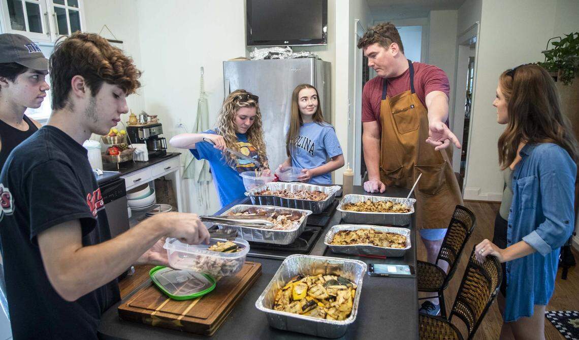 Tom and Rachael Sullivan, at right, share food with college students Tuesday, July 6, 2021 at their home in Raleigh. The Sullivans started offering free food for college students after they went viral on Ticktock and, what started out as Tom’s secret Instagram account to keep track of Rachaelís favorite meals, @mealssheeats, gained more than 70k followers in two months.