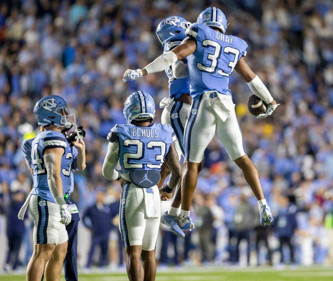 North Carolina’s Cedric Gray (33) and teammate Tayon Holloway (20) celebrate Gray’s interception of Miami quarterback Tyler Van Dyke in the third quarter on Saturday, October 14, 2023 at Kenan Stadium in Chapel Hill, N.C.