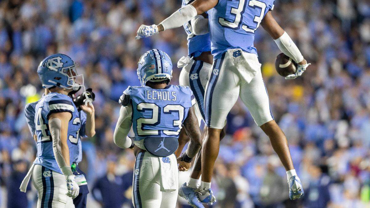 North Carolina’s Cedric Gray (33) and teammate Tayon Holloway (20) celebrate Gray’s interception of Miami quarterback Tyler Van Dyke in the third quarter on Saturday, October 14, 2023 at Kenan Stadium in Chapel Hill, N.C.