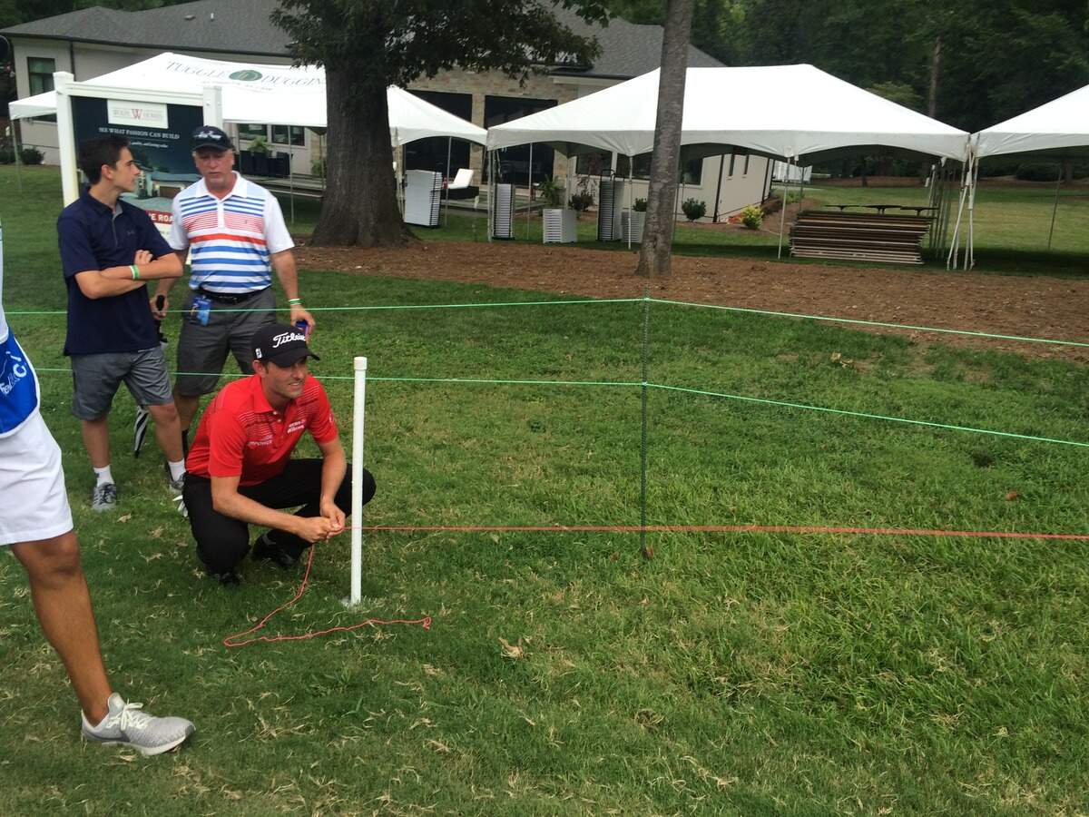 Webb Simpson uses a string to determine whether his drive on the 18th hole Sunday was out of bounds. It was ruled in bounds, but Simpson made his only bogey of the day to finish tied for second in the Wyndham Championship.