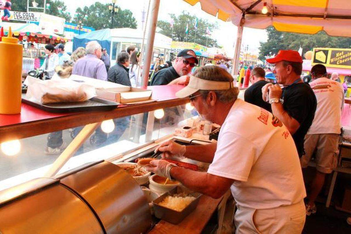 Billy Barefoot, left, prepares a hot dog at Charlie Barefoot and Sons, a fixture at the State Fair since 1949. The beloved vendor won’t be at the 2026 NC State Fair. 
