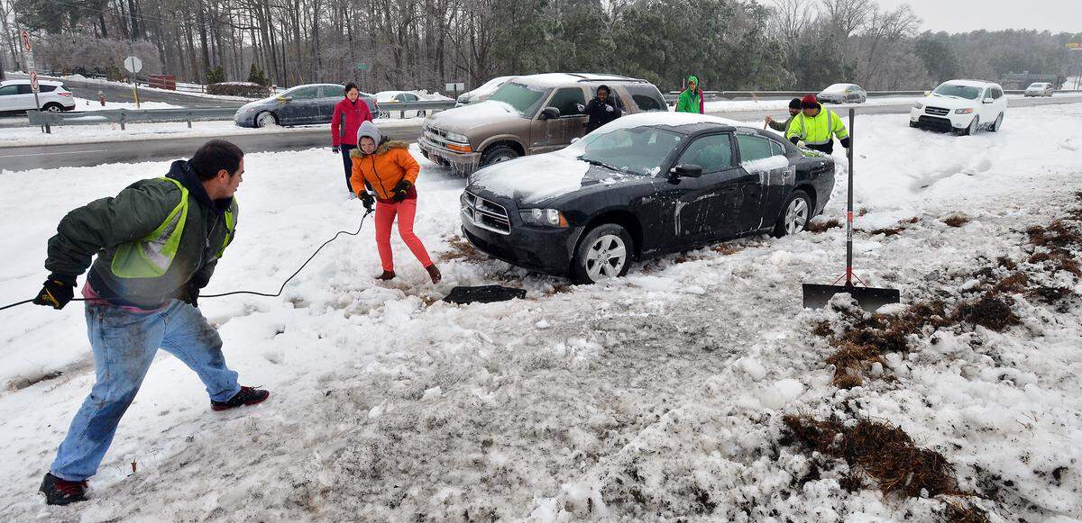 Priscilla Hernandez (pink coat) watches as a wrecker crew pulls her vehicle from the median on Hwy 70 near I-540 Thursday Feb. 13, 2014. Hernandez was ecstatic when the crew pulled her car out of the ditch without causing any damage.