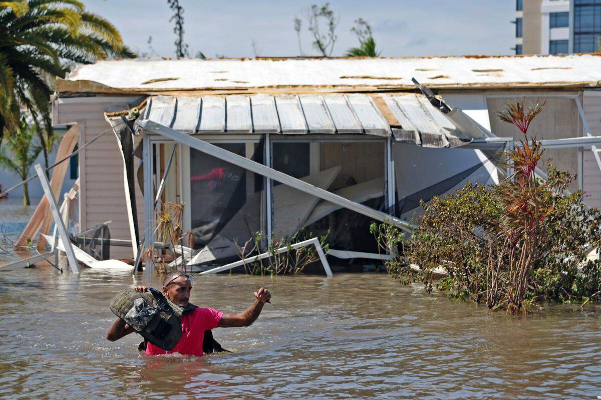 Jonathan Strong holds his vest above the water as he wades through floodwaters while knocking on doors in a flooded mobile home community in Iona, an unincorporated community in Lee County near Fort Myers, Fla., Thursday, Sept. 29, 2022. Strong, who is unaffiliated with any volunteer group, said he came out to help because, “I can’t just sit around while my house is intact and let other people suffer. It’s what we do; community helping community.” Hurricane Ian made landfall Wednesday, Sept. 28, as a Category 4 hurricane on the southwest coast of Florida.