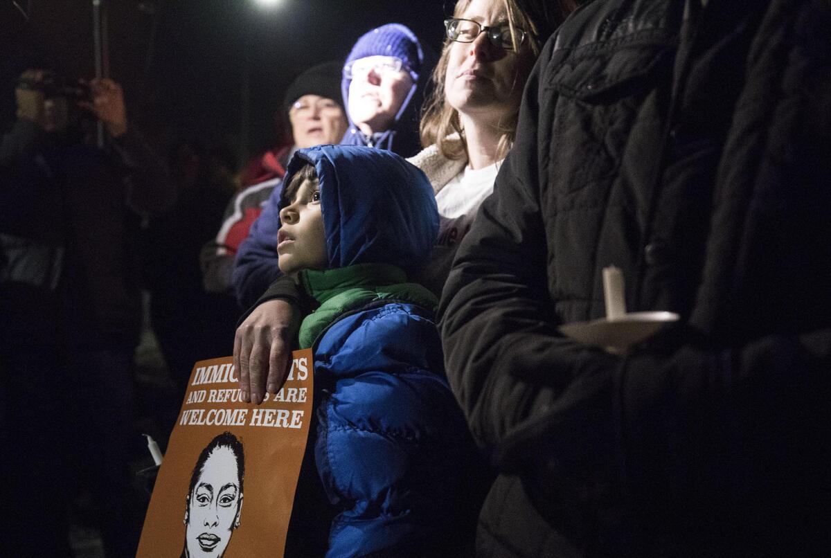 Mikey Olvera-Maldonado, 8, listens to speakers at the vigil for Samuel Oliver-Bruno on Tuesday with his mother, Susan, who was one of 27 people arrested Friday for trying to block the van carrying Samuel from the USCIS office to ICE detention last Friday.