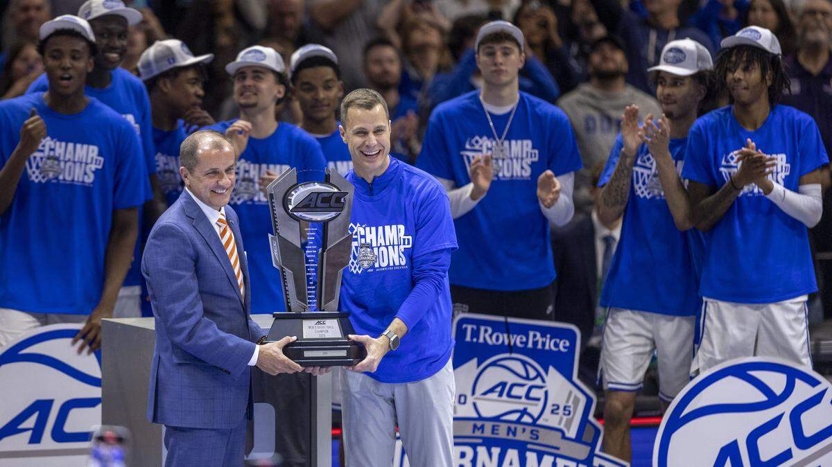 Duke coach John Scheyer accepts the ACC Tournament Championship trophy from Commissioner Jim Phillips following the Blue Devils’ 73-62 victory over Louisville in the ACC Tournament Championship game on Saturday, March 15, 2025 at Spectrum Center in Charlotte, N.C.