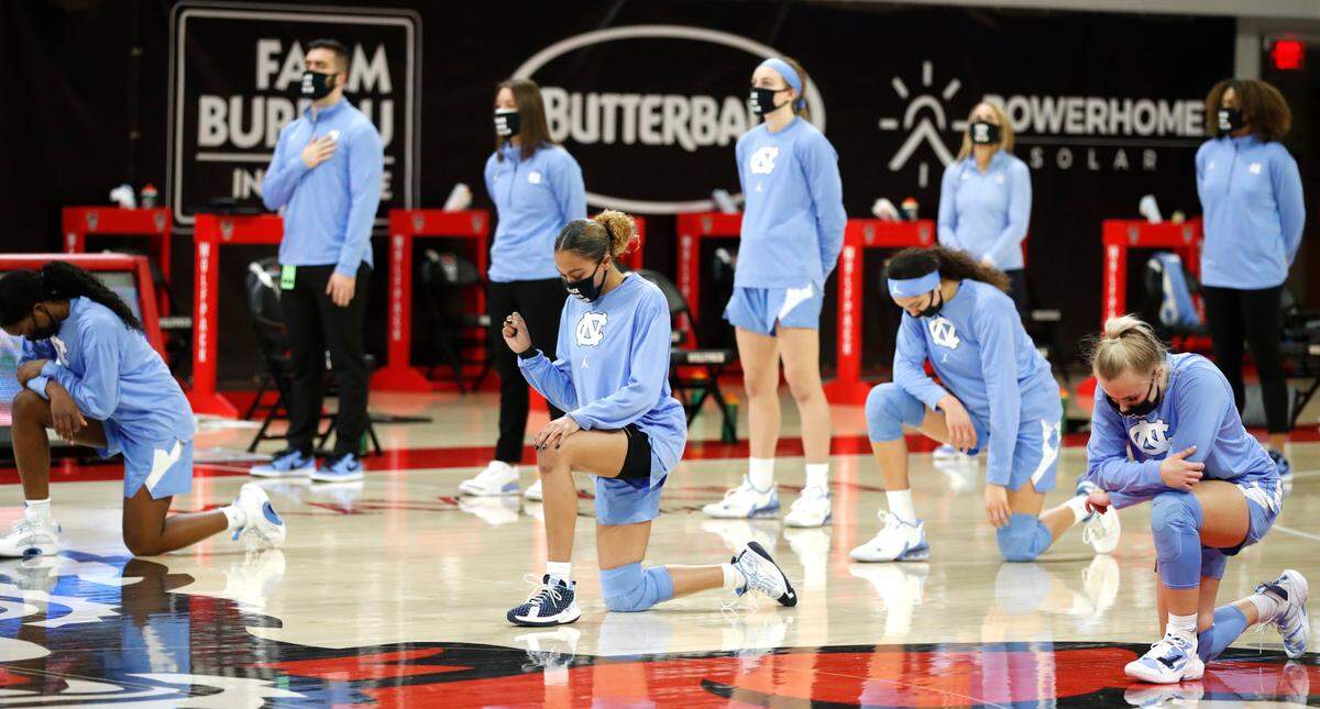 Some North Carolina players, including Stephanie Watts, center, kneel during the national anthem before N.C. State’s game against UNC in the annual Play4Kay game at Reynolds Coliseum in Raleigh, N.C., Sunday, February 21, 2021.
