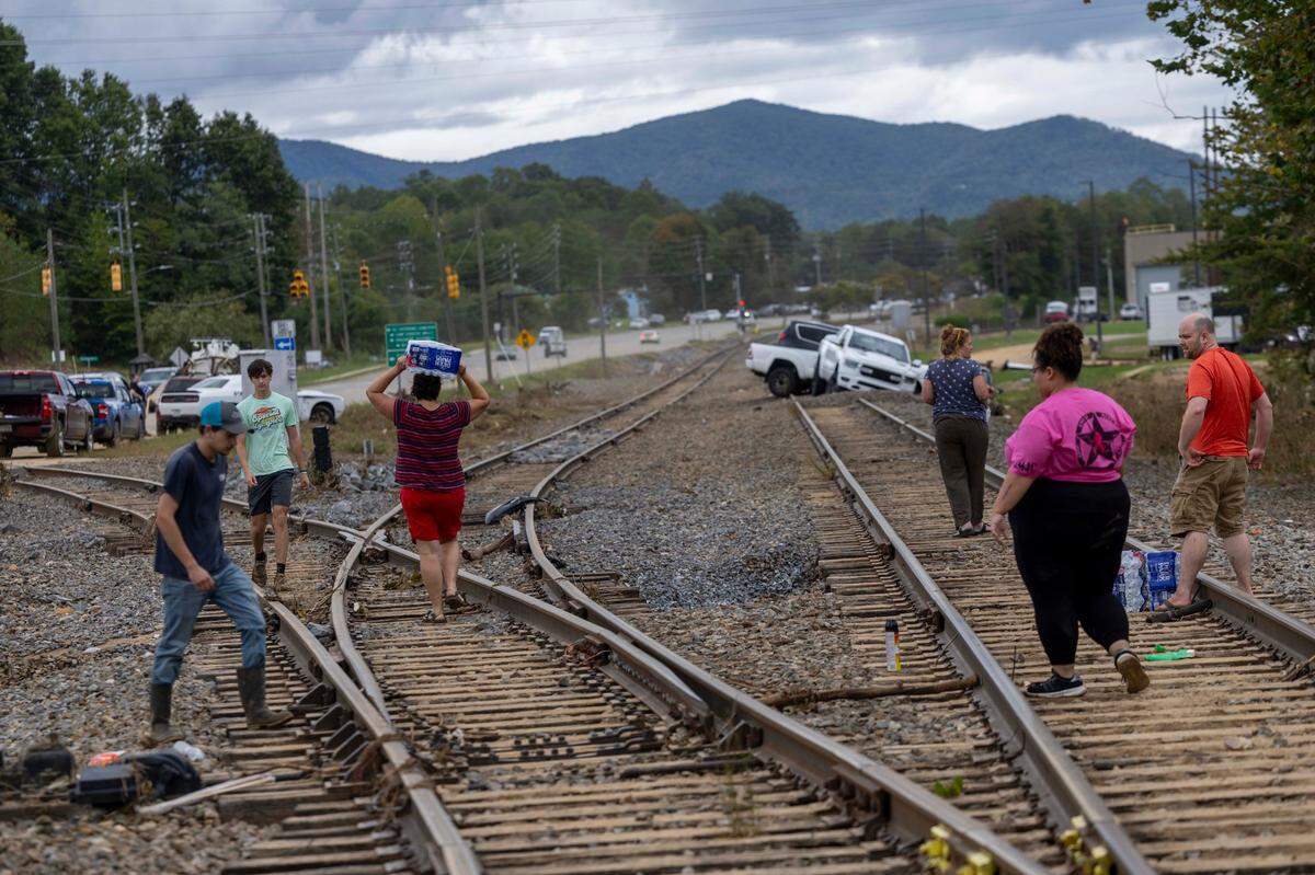 Western North Carolina residents salvage bottled water from a flooded tractor-trailer in Swannanoa on Sunday, Sept. 29, 2024. The remnants of Hurricane Helene caused widespread flooding, downed trees, and power outages in western North Carolina.