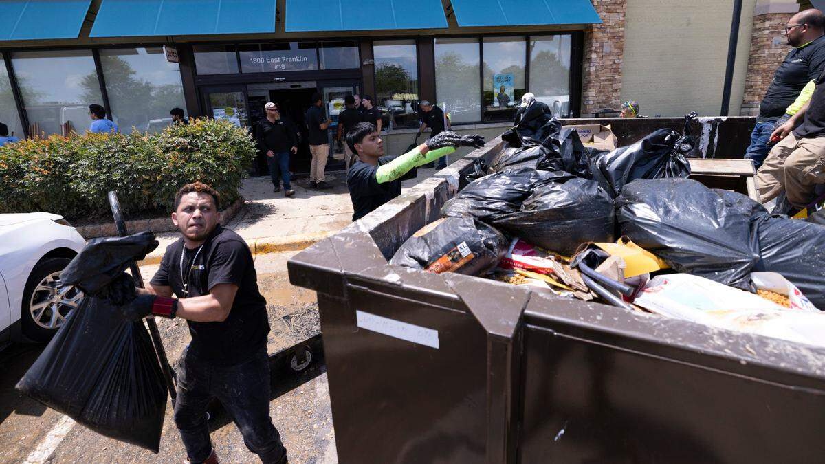 Workers discard thousands of dollars worth of flooded pet food and supplies at a Petco in Eastgate Crossing in Chapel Hill on Monday, July 7, 2025, after floodwaters surged about 5 feet inside businesses at the shopping center. The flooding was caused by heavy rain from Tropical Storm Chantal, which triggered flash flooding in parts of Orange, Durham, and Chatham counties.