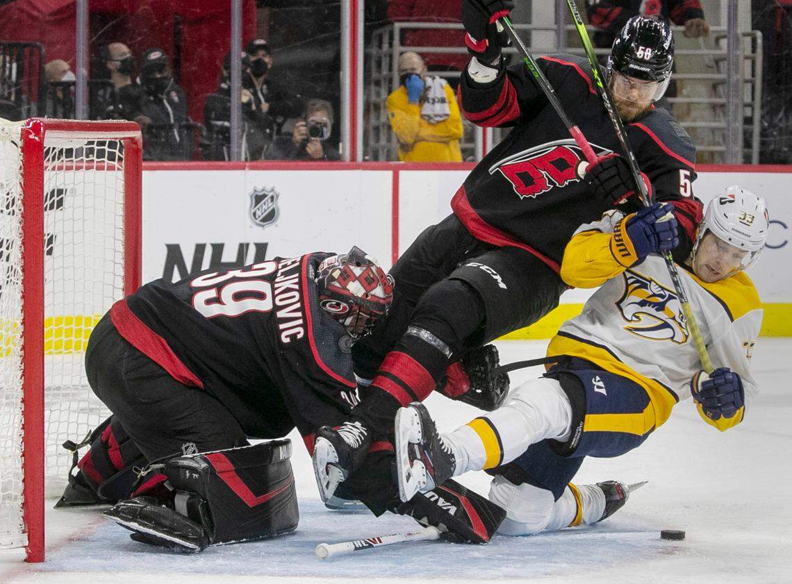 Carolina Hurricanes’ Jani Hakanpaa (58) checks Nashville’s Viktor Arvidsson (33) to the ice in front of Hurricanes’ goalie Alex Nedeljkovic (39) during the first period in their first round Stanley Cup series game on Monday, May 17, 2021 at PNC Arena in Raleigh, N.C.