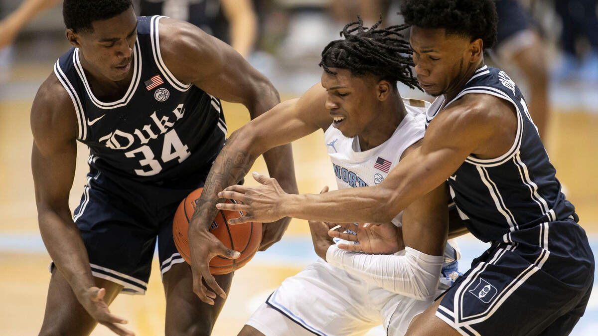 Duke’s Henry Coleman III (34) and Jeremy Roach (3) trap North Carolina’s Caleb Love (2) during the second half on Saturday, March 6, 2021 at the Smith Center in Chapel Hill, N.C.