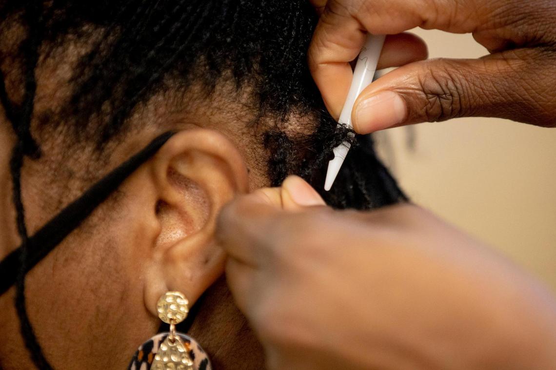 Denise Browning, left, has her Sisterlocks retightened in The Barbee Shop by Wendi Barbee, right, on Friday, Jan. 15, 2021, in Durham, N.C.