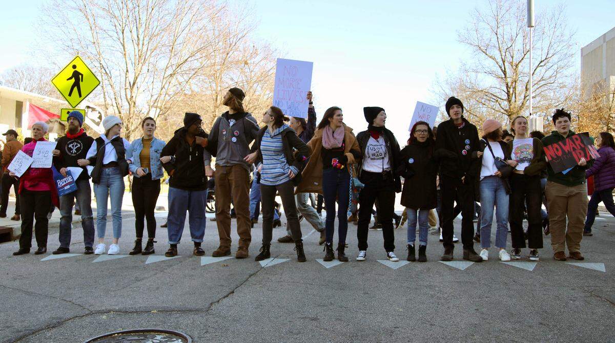 Protesters lock arms to block the street and allow others to pass behind them during anti-war protests in Raleigh, N.C. on January 5, 2020.