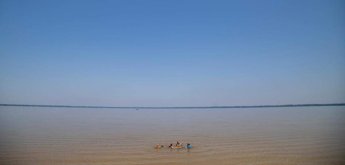 Children from the Brunswick County Wild + Free homeschool group play in the shallow water at Lake Waccamaw State Park.