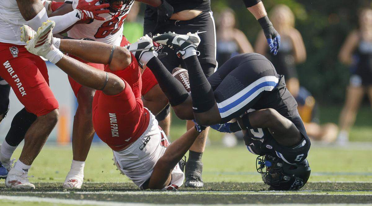 The forward progress of Duke running back Jaquez Moore (9) was stopped before he fumbled while being hit by N.C. State defensive end Travali Price (13) during the first half of N.C. State’s game against Duke at Wallace Wade Stadium in Durham, N.C., Sat. Sept. 20, 2025