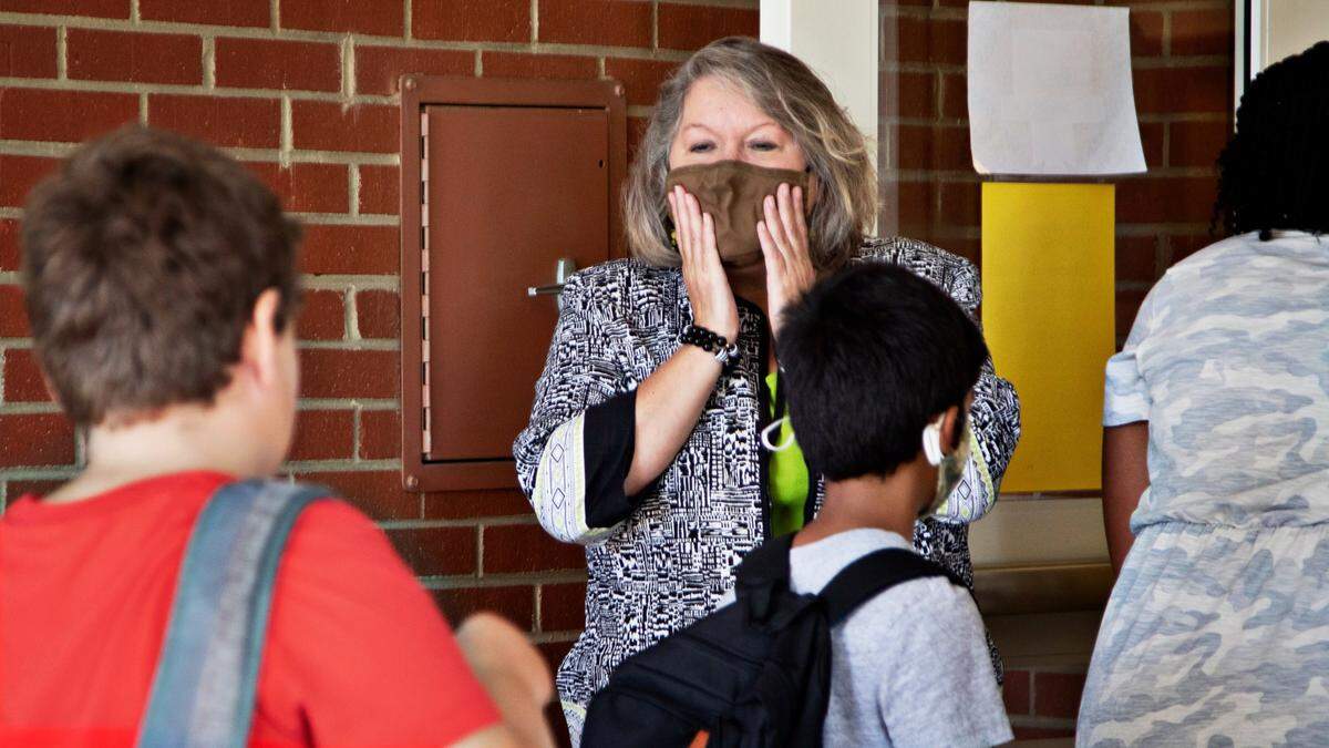 Principal Fay Jones, center, reminds students to pull up their masks as they enter Carpenter Elementary School in Cary on Thursday morning, Aug. 19, 2021. Some North Carolina school districts are now dropping face mask mandates for the first time since the start of the COVID-19 pandemic nearly two years ago.