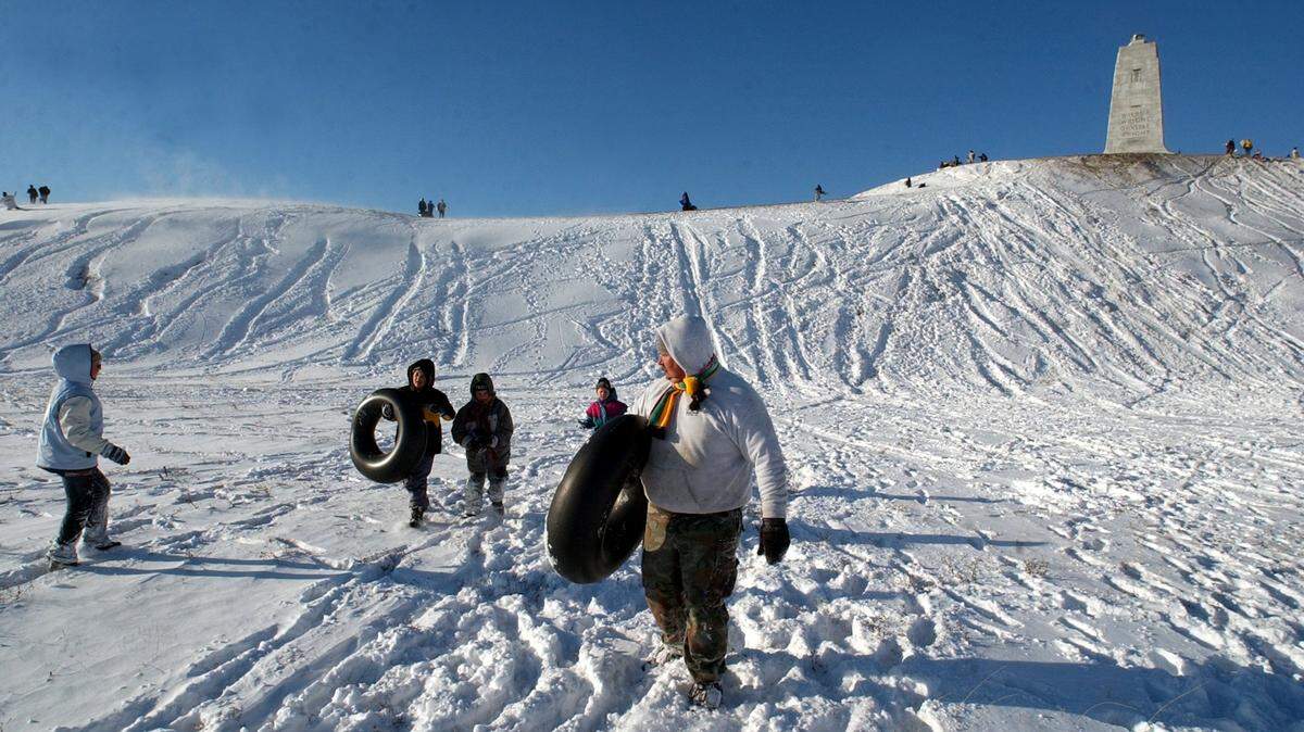 After a couple of hours on the steep slopes at the Wright Brothers Memorial Dave Robertson gathers up his three children and heads back to their car on after a winter storm dumped several inches of snow on the Outer Banks in January 2002.