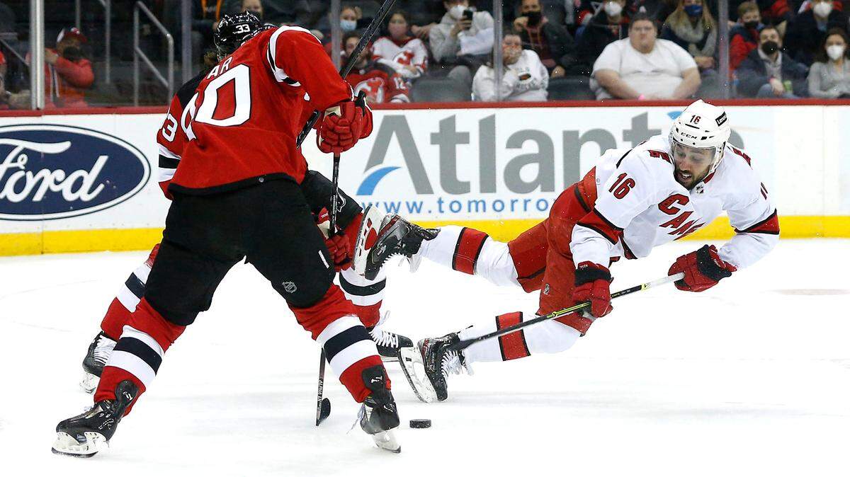 Carolina Hurricanes center Vincent Trocheck (16) plays the puck against New Jersey Devils left wing Tomas Tatar (90) during the first period of an NHL hockey game, Saturday, Jan. 22, 2022, in Newark, N.J. (AP Photo/Noah K. Murray)
