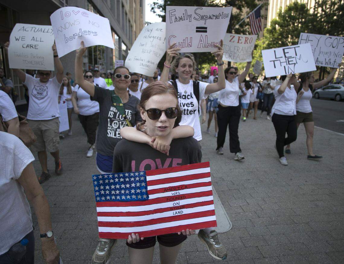 Maggie Duffy of Raleigh takes part in the 'Families Belong Together' march along the sidewalk on Fayetteville Street on Saturday, June 30, 2018. After gathering on the City Plaza, thousands marched to Bicentennial Plaza for a rally on immigration reform.