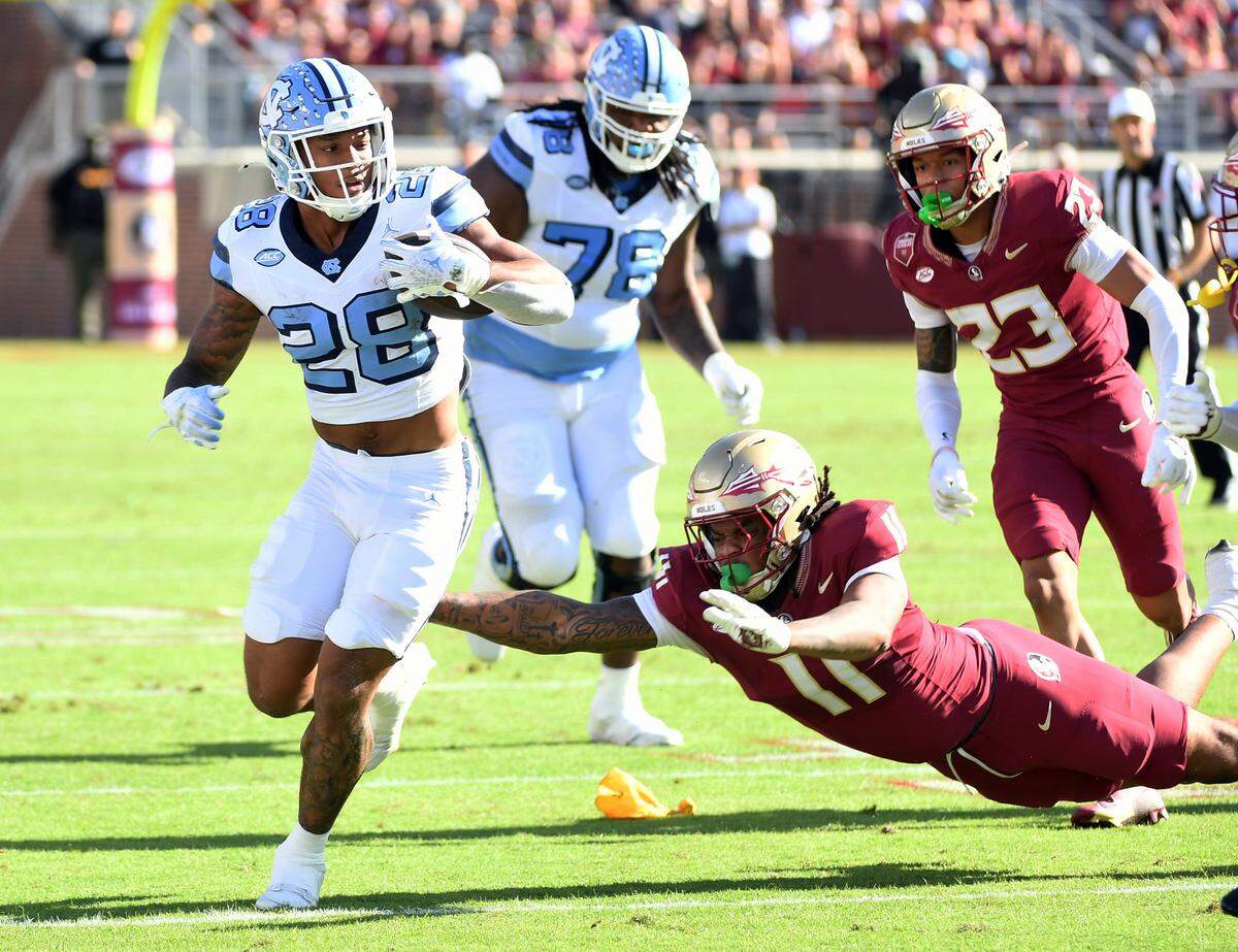 Nov 2, 2024; Tallahassee, Florida, USA; North Carolina Tarheels running back Omarian Hampton (28) runs the ball past Florida State Seminoles defensive end Patrick Payton (11) during the first quarter at Doak S. Campbell Stadium.