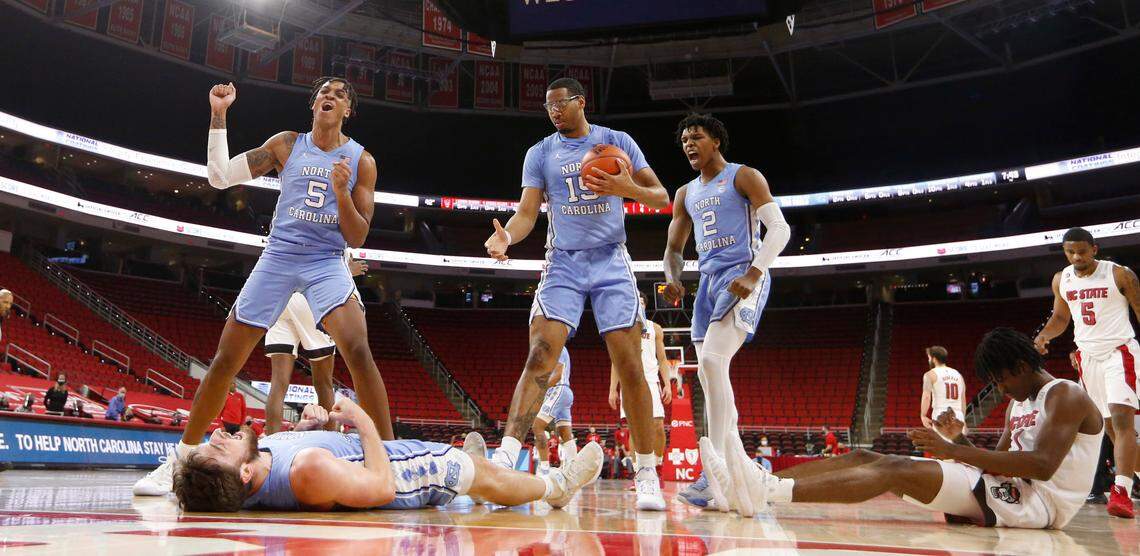 North Carolina’s Armando Bacot (5) and Caleb Love (2) celebrate with Andrew Platek (3) after N.C. State’s Dereon Seabron (1), right, was called for a charging foul during N.C. State’s 79-76 victory over UNC at PNC Arena in Raleigh, N.C., Tuesday, December 22, 2020. North Carolina’s Garrison Brooks (15) helps Platek up.