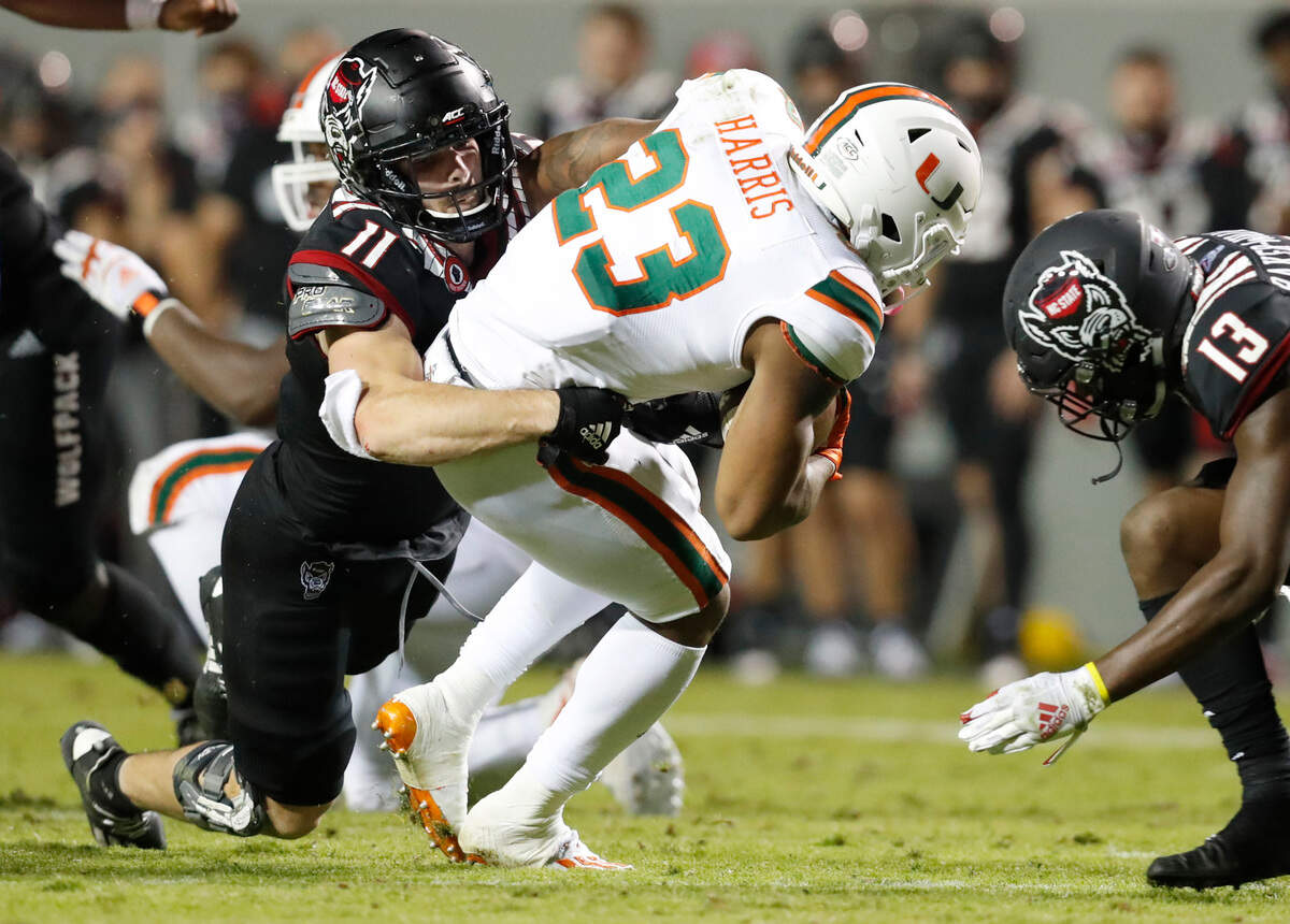 N.C. State linebacker Payton Wilson (11) tackles Miami running back Cam’Ron Harris (23) as N.C. State defensive back Tyler Baker-Williams (13) comes in during the second half of Miami’s 44-41 victory over N.C. State at Carter-Finley Stadium in Raleigh, N.C., Friday, Nov. 6, 2020.