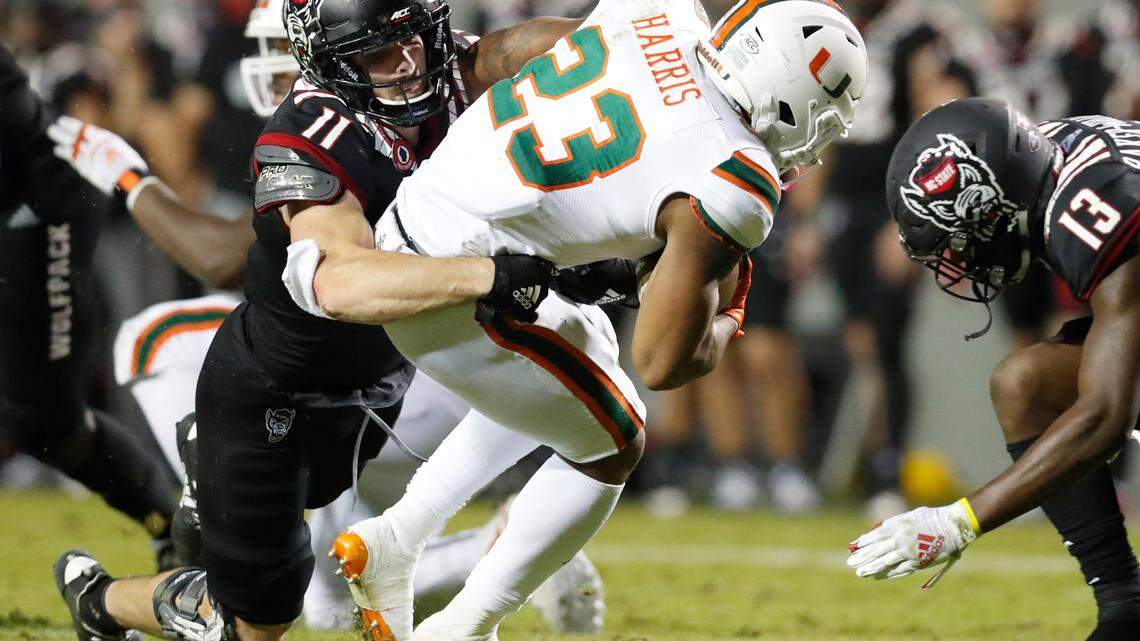 N.C. State linebacker Payton Wilson (11) tackles Miami running back Cam’Ron Harris (23) as N.C. State defensive back Tyler Baker-Williams (13) comes in during the second half of Miami’s 44-41 victory over N.C. State at Carter-Finley Stadium in Raleigh, N.C., Friday, Nov. 6, 2020.