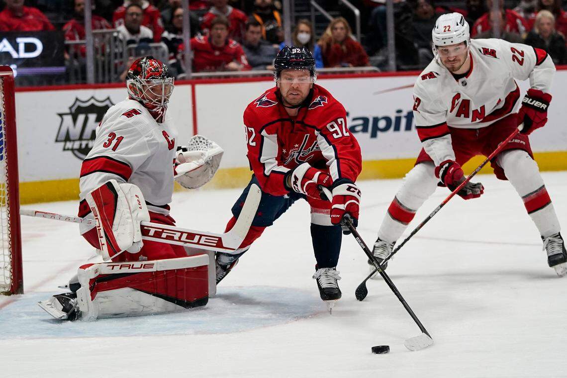 Washington Capitals center Evgeny Kuznetsov (92) works the puck in front of Carolina Hurricanes goaltender Frederik Andersen (31) with Hurricanes defenseman Brett Pesce (22) defending in the first period of an NHL hockey game, Monday, March 28, 2022, in Washington. (AP Photo/Alex Brandon)