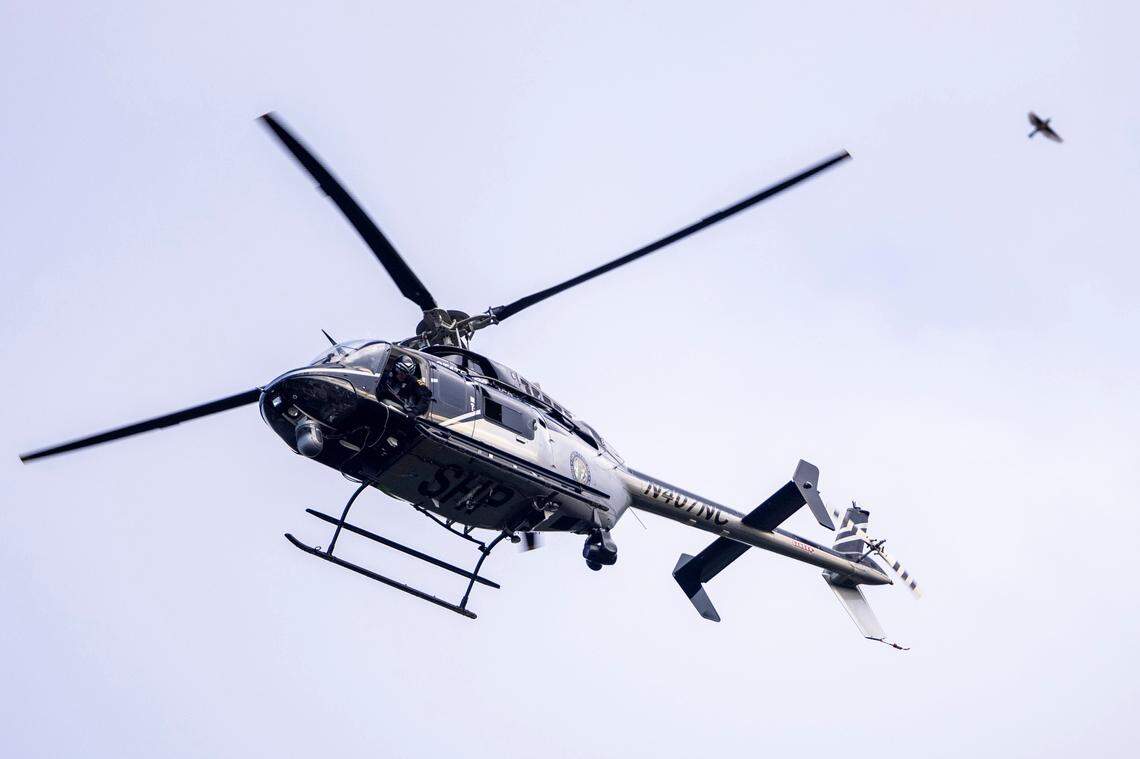 A North Carolina State Highway Patrol helicopter flies over a search area Friday, July 29, 2022 in Fuquay-Varina, NC after a twin-engine turboprop aircraft made an emergency landing at RDU International Airport and skidded off the runway. A person exited the plane prior to the emergency landing and was found dead in a Fuquay-Varina residential backyard.
