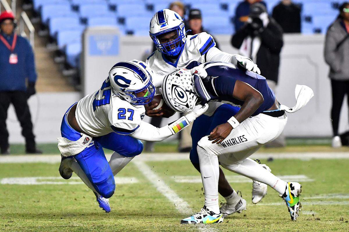 Clayton's Keshawn Stancil (8) and defensive lineman Kaden Blackwell (27) grapple Grimsley quarterback Faizon Brandon (11) during the first half.  The Clayton Comets and the Grimsley Whirlies met in the NCHSAA 7A football Championships in Chapel Hill, NC on December 12, 2025.