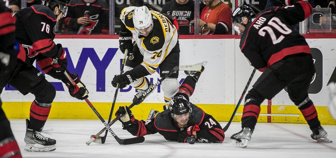 Carolina Hurricanes’s Seth Jarvis (24) eyes the puck from ice level beneath Boston’s Jake DeBrusk (74) during the first period on Saturday, May 14, 2022 during game seven of the Stanley Cup first round at PNC Arena in Raleigh, N.C.