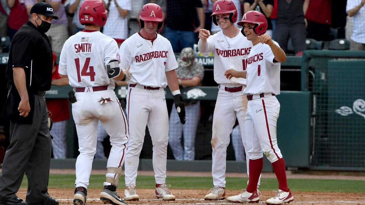 Arkansas batter Cullen Smith (14) is greeted by teammates Cayden Wallace (7), Matt Goodheart (10) and Robert Moore (1) after hitting a grand slam against North Carolina State in the second inning of an NCAA college baseball super regional game Friday, June 11, 2021, in Fayetteville, Ark. (AP Photo/Michael Woods)