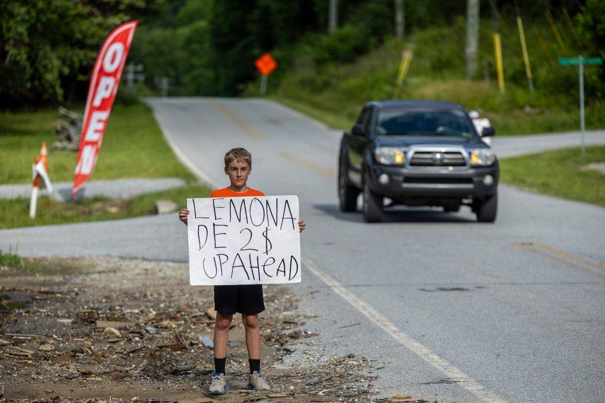 Clayton Donaldson, 12, sells lemonade along U.S. 74A in Gerton on Friday, June 13, 2025, near Bat Cave. A temporary road now connects Bat Cave and Chimney Rock after Hurricane Helene destroyed a 2.5-mile stretch of U.S. 64/74A through Hickory Nut Gorge—one of the most severely damaged and costly road repairs in the state.