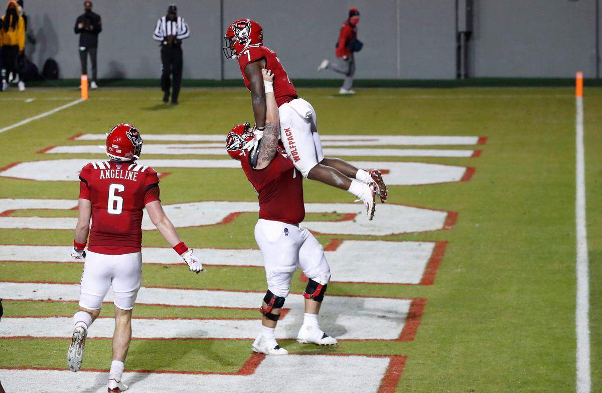 N.C. State’s Joe Sculthorpe (71) holds up Zonovan ‘Bam’ Knight (7) after he scored on a 17-yard touchdown run during the first half of N.C. State’s game against Liberty at Carter-Finley Stadium in Raleigh, N.C., Saturday, Nov. 21, 2020.