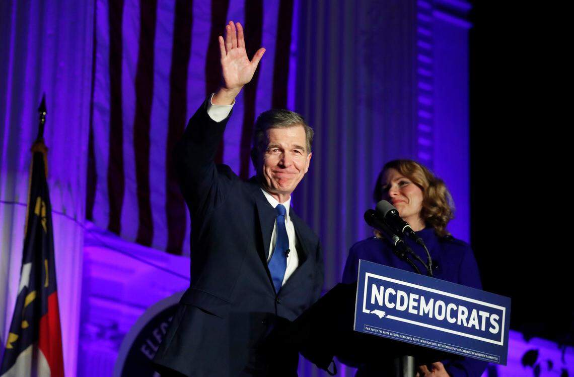 Gov. Roy Cooper waves after speaking outside the North Carolina Democratic Party headquarters in Raleigh, N.C., Tuesday, Nov. 3, 2020. Next to Cooper is his wife, Kristin Cooper.