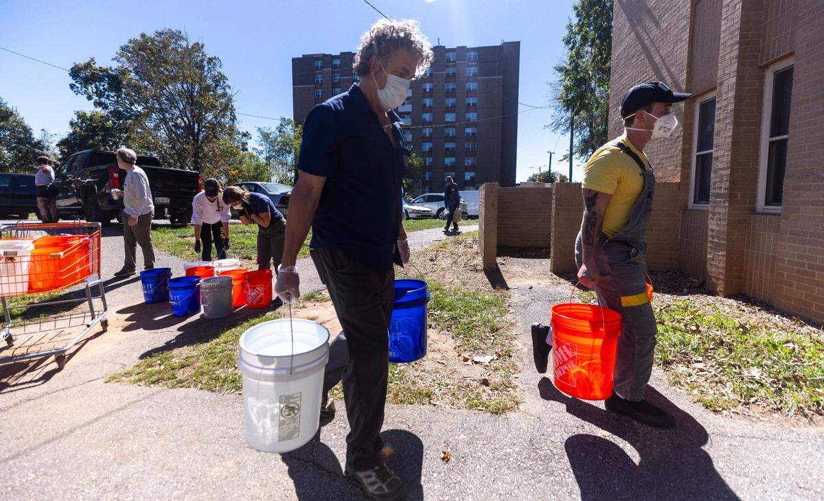 Volunteers organized by grassroots group BeLoved Asheville haul gray water to help residents in low-income independent living facilities, with no running water, flush their toilets on Wednesday, Oct. 9, 2024. About half of Asheville’s water customers were still without running water this week because the remnants of Hurricane Helene ripped apart the city’s distribution system.