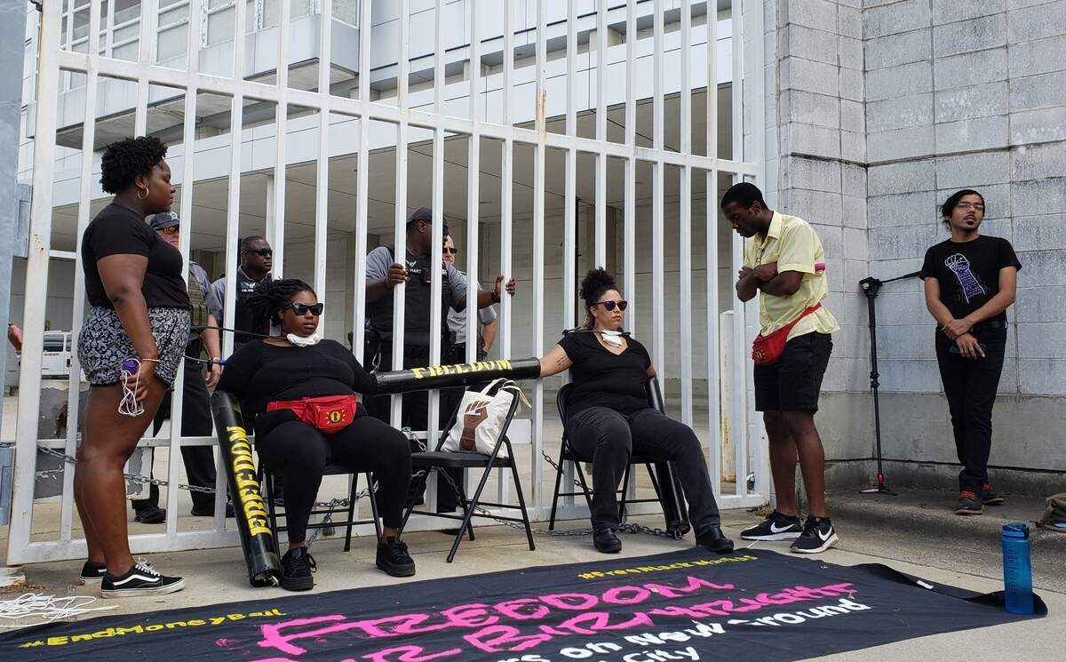 Southerners On New Ground organizers Kyla Hartsfied, left, and Serena Sebring, chained themselves to a gate at the Durham County jail Thursday, May 9, 2019, as a Sheriff’s Office deputies attempt to speak with them about safety concerns.