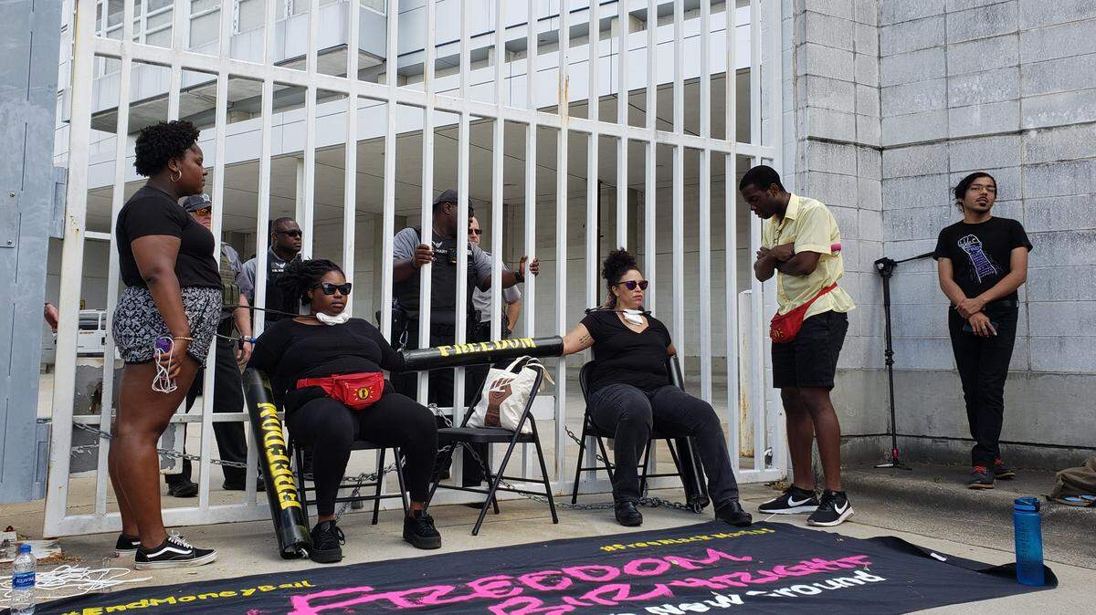 Southerners On New Ground organizers Kyla Hartsfied, left, and Serena Sebring, chained themselves to a gate at the Durham County jail Thursday, May 9, 2019, as a Sheriff’s Office deputies attempt to speak with them about safety concerns.