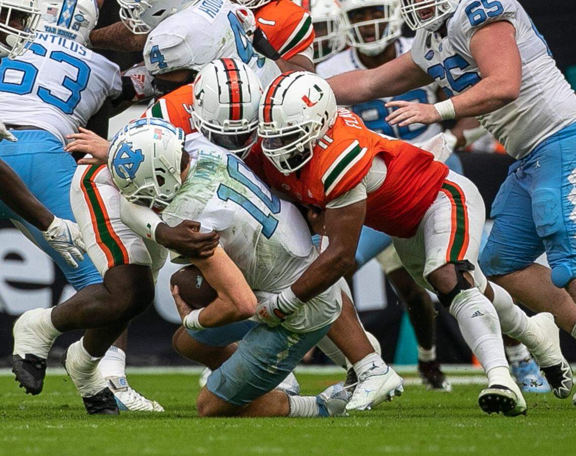 Miami’s Corey Flagg Jr. (11) and Nyjalik Kelly (32) sack North Carolina quarterback Drake Maye (10) for a loss in the third quarter on Saturday, October 8, 2022 at Hard Rock Stadium in Miami Gardens, Florida.