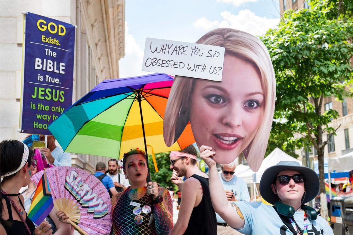 Pride festivalgoers hold up umbrellas and signs to block out individuals preaching over loud speakers and holding signs with anti-LGBTQ+ messages at Raleigh Pride on Saturday, June 22, 2024.
