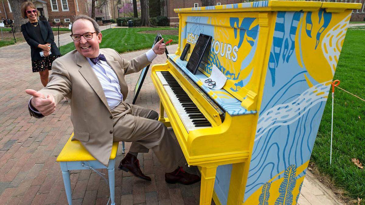 UNC Law School Dean Martin Brinkley finishes playing a tune one on of UNC's painted pianos April 6, 2018, as UNC Chancellor Carol Folt looks on.  The pianos are part of the Arts Everywhere installations around the campus of the University of North Carolina at Chapel Hill.