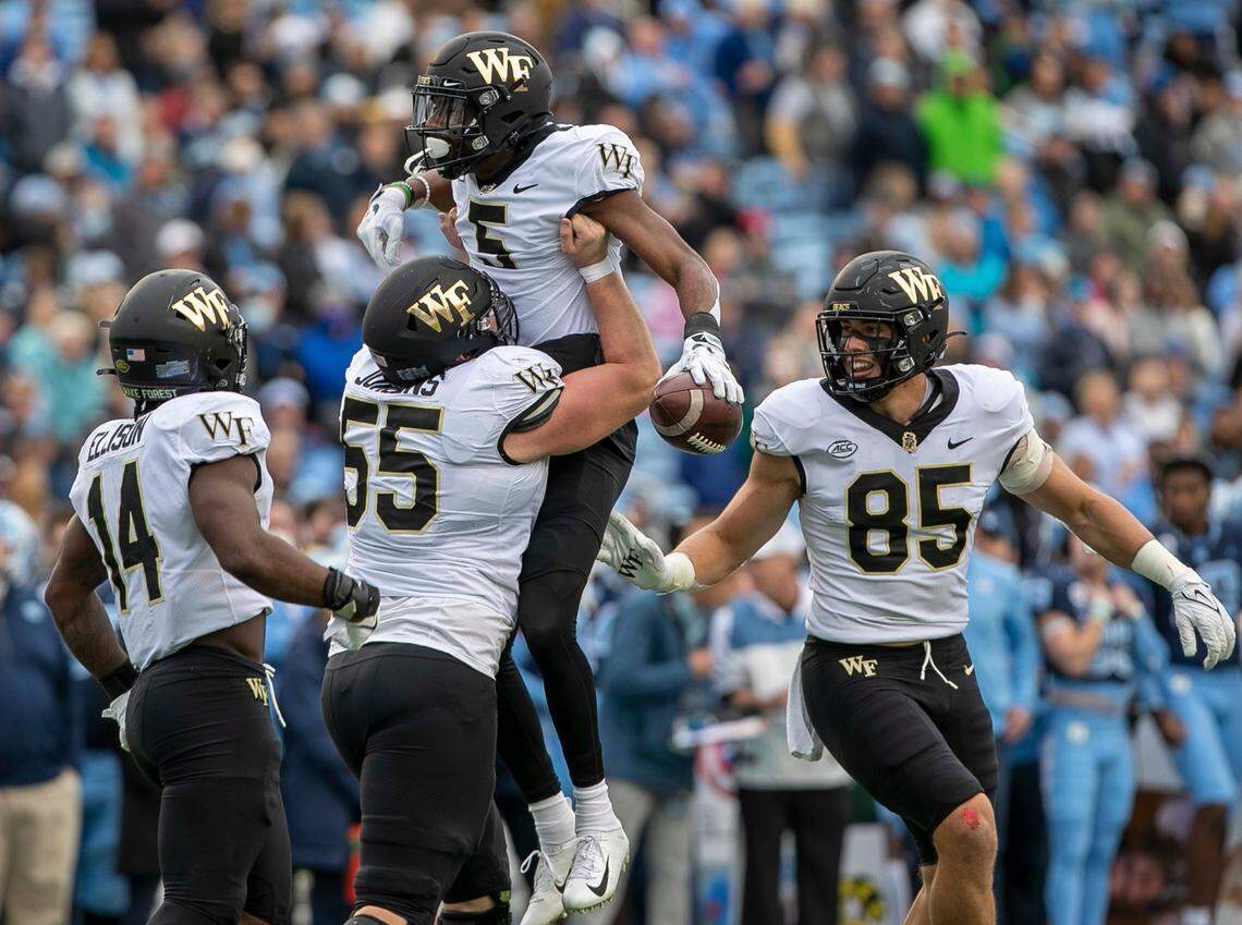 Wake Forest’s Michael Jurgens (55) hoists teammate Jaquari Roberson (5) as they celebrate following a 15-yard pass reception for a touchdown in the second quarter against North Carolina on Saturday, November 6, 2021 at Kenan Stadium in Chapel Hill, N.C.