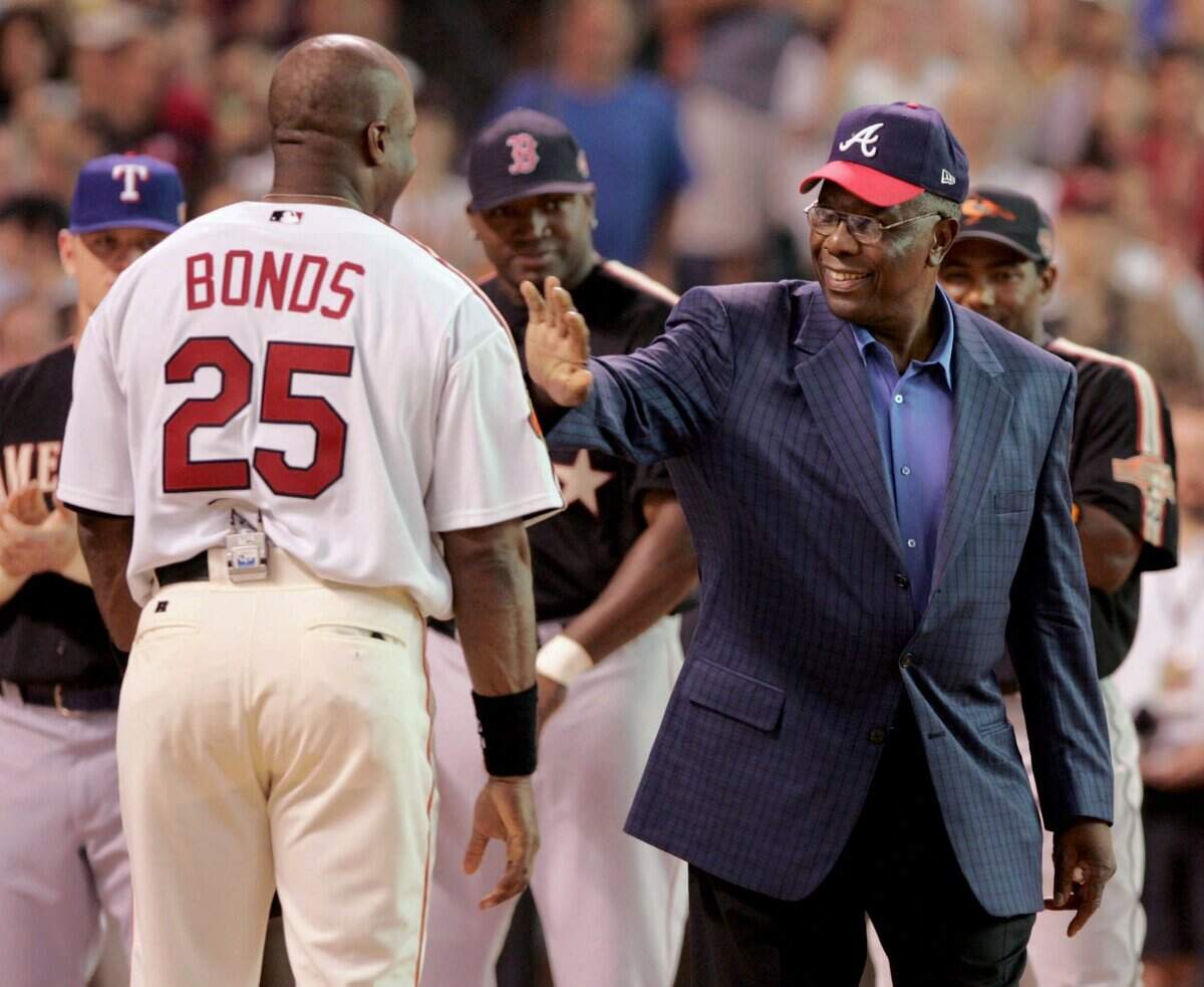 In this July 12, 2004, file photo, home run record holder Hank Aaron greets San Francisco Giants slugger Barry Bonds before the start of the All-Star Home Run Derby in Houston. Hank Aaron, who endured racist threats with stoic dignity during his pursuit of Babe Ruth’s home run record and gracefully left his mark as one of baseball’s greatest all-around players, died Friday. He was 86. The Atlanta Braves, Aaron’s longtime team, said he died peacefully in his sleep. No cause was given.