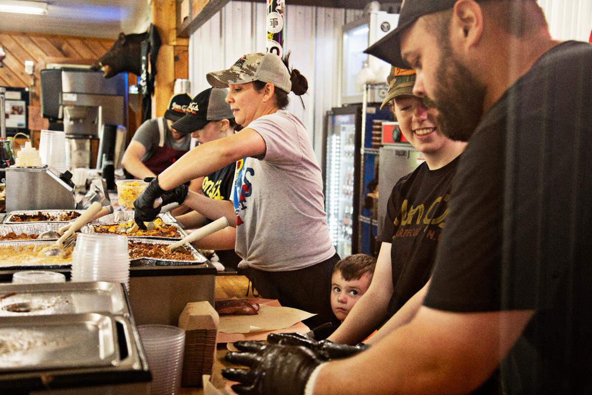 Jon G’s Barbecue is a family affair with Kelly Kirkman, center, son, Gil, and firekeeper Jon Garren Kirkman, far right, on the line Saturday morning, June 25, 2022.