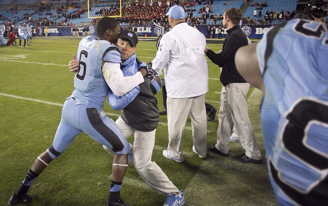 UNC’s Sean Tapley (6) holds coach Larry Fedora as teammates and Kareem Martin and Eric Ebron arrive with a victory bath as they celebrate the Tar Heels’ 39-17 victory over Cincinnati on Saturday December 28, 2013 during the Belk Bowl at Bank Of America Stadium in Charlotte, N.C. Fedora was able to duck and avoid the victory bath.