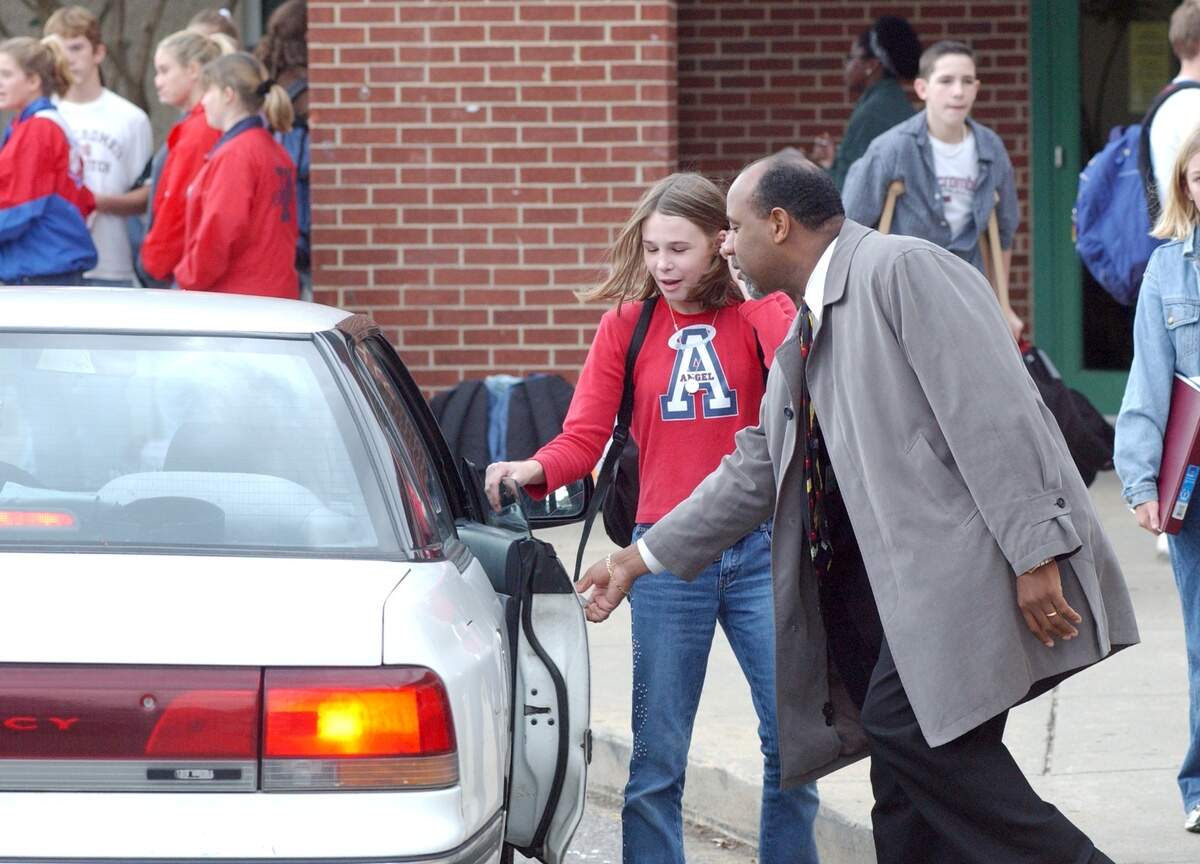 Wake Forest-Rolesville Middle School principal Marvin Connelly opens the car door in this 2002 file photo for 6th-grader Ashley Moore as students who are getting picked up rather than riding the bus wait for their rides.