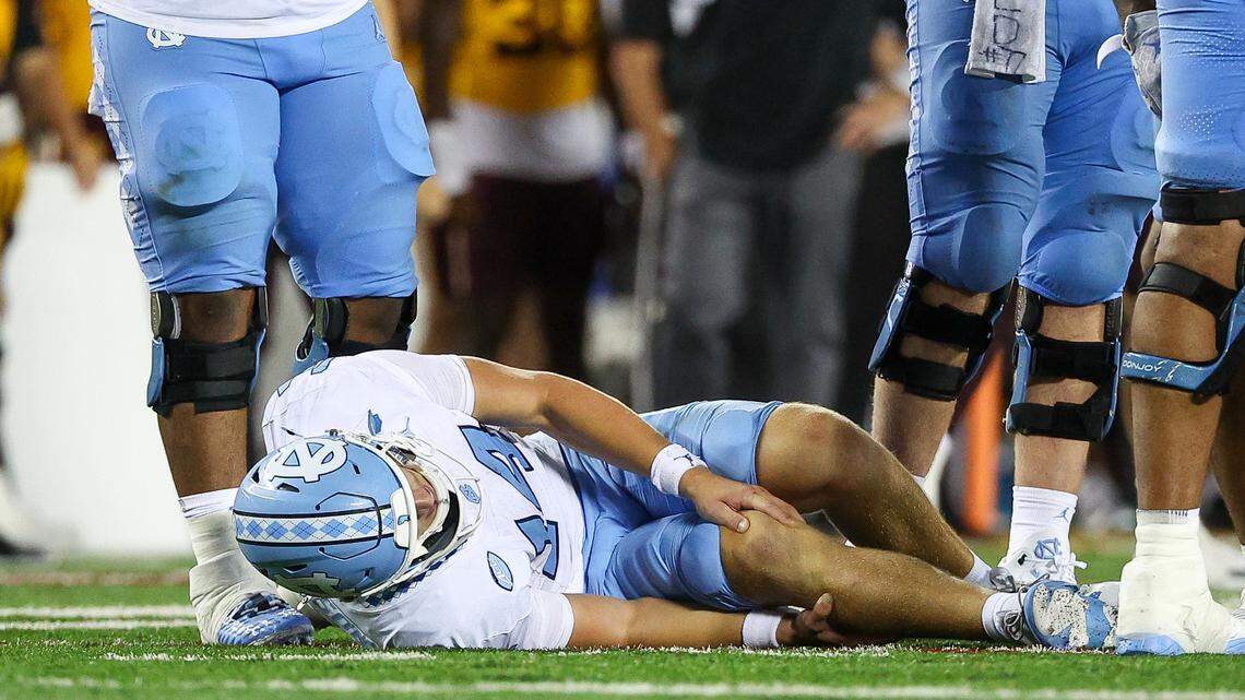 Aug 29, 2024; Minneapolis, Minnesota, USA; North Carolina Tar Heels quarterback Max Johnson (14) grabs his knee after being tackled during the second half against the Minnesota Golden Gophers at Huntington Bank Stadium. Mandatory Credit: Matt Krohn-USA TODAY Sports